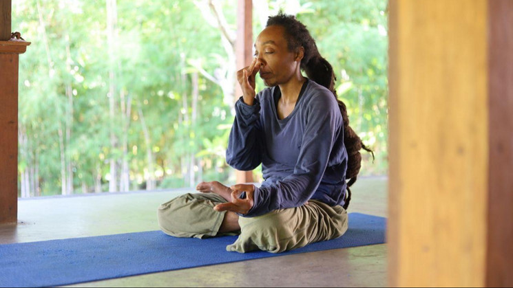 Mwzimba practicing breathwork in an open wooden room